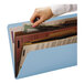A hand putting a paper into a Smead SafeSHIELD file folder.