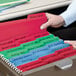 A person's hand holding a Smead FasTab letter size hanging file folder in green and white.
