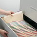 A hand pulling a Smead file folder from a file drawer.
