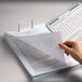 A hand holding a piece of paper over a Smead fastener folder.