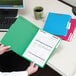 A person holding a green Smead file folder with papers inside.