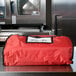 An American Metalcraft red nylon pizza delivery bag on a counter.