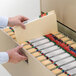 A person holding a file drawer with several Smead manila file folders.