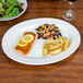 A CAC Garden State bone white oval porcelain platter with a salad and lemon slices on a table.