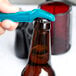 A person using a Franmara turquoise plastic bottle opener to open a brown bottle.