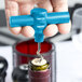 A hand using a Franmara turquoise plastic pocket corkscrew to open a wine bottle with a cork.