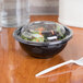 a bowl of salad with a plastic lid and a plastic spoon