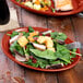 A Fiesta Scarlet oval small china platter with salad and a fork on a table.