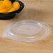 A Fabri-Kal plastic container with a vented lid holding a bowl of oranges.