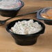 Two Fabri-Kal black plastic SideKicks bowls with food in them.