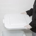 A person in gloves and a white coat holding a Rubbermaid white square lid.