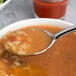 A Chef & Sommelier stainless steel soup spoon in a bowl of soup.