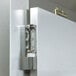 A close-up of a Traulsen Correctional Roll Thru Refrigerator metal door hinge with a lock.