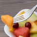 A Chef & Sommelier stainless steel dessert fork holding a piece of fruit.