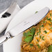 A plate of chicken and rice with a Chef & Sommelier stainless steel dinner knife on the table.