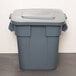 A Rubbermaid gray plastic square trash can with a lid.