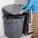 A person opening a Rubbermaid commercial trash can.