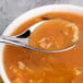 A Chef & Sommelier stainless steel soup spoon full of soup in a bowl.