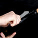 A person using a Laguiole champagne saber to open a bottle of champagne.