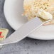 A Chef & Sommelier butter spreader on a plate with a piece of bread and butter.