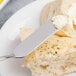 An Arcoroc stainless steel butter spreader on a piece of bread.