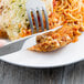 A Libbey stainless steel steak knife with a fluted blade cutting into a plate of food.
