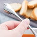 A hand holding a Libbey stainless steel bouillon spoon over a bowl of soup.