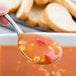 A Libbey stainless steel bouillon spoon holding a spoonful of soup.