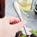 A hand holding a Libbey stainless steel salad fork over a salad