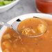 An Arcoroc stainless steel soup spoon in a bowl of soup.