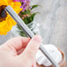 A hand holding a Libbey 18/0 stainless steel dessert spoon over a cup of chocolate.