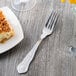 A Libbey stainless steel utility/dessert fork on a plate with food.