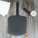 An Epicurean Richlite wood pizza peel with a black handle on a wood surface.