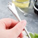 A hand holding a Libbey stainless steel salad fork over a yellow bowl on a counter.