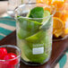 An American Metalcraft beaker glass filled with lime wedges and cherries on a counter.