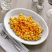 A white Tuxton oval china platter with a plate of macaroni and cheese and a fork.