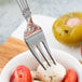 A Libbey stainless steel cocktail fork holding mozzarella cheese and tomatoes.