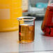 An American Metalcraft beaker glass with brown liquid in it.