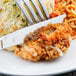 A Libbey Lady Astor stainless steel knife with a fluted blade next to a fork on a plate of food.