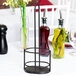 A black metal Tablecraft Gemelli cruet rack with oil bottles on a table.