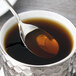 An Arcoroc stainless steel teaspoon in a cup of liquid.