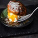 A Libbey stainless steel dessert spoon on a plate with food.