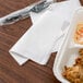 A white 1/4 fold luncheon napkin on a white tray with food.