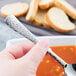 A person holding a Libbey stainless steel bouillon spoon over a bowl of soup.