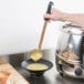 A hand using a Vollrath Jacob's Pride ladle to pour soup into a bowl.