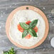 A pizza with tomatoes and basil on a Epicurean Richlite pizza board.