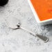 A Libbey stainless steel bouillon spoon next to a bowl of soup.