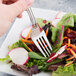 A Libbey stainless steel salad fork in a vegetable salad.