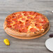 A pepperoni pizza on a wood surface served on an Epicurean Richlite wood pizza board.