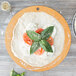 An Epicurean natural wood fiber pizza board with pizza dough, tomatoes and basil on top.